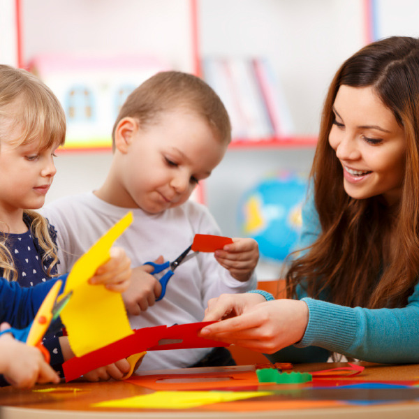 Teacher helping students with scissors