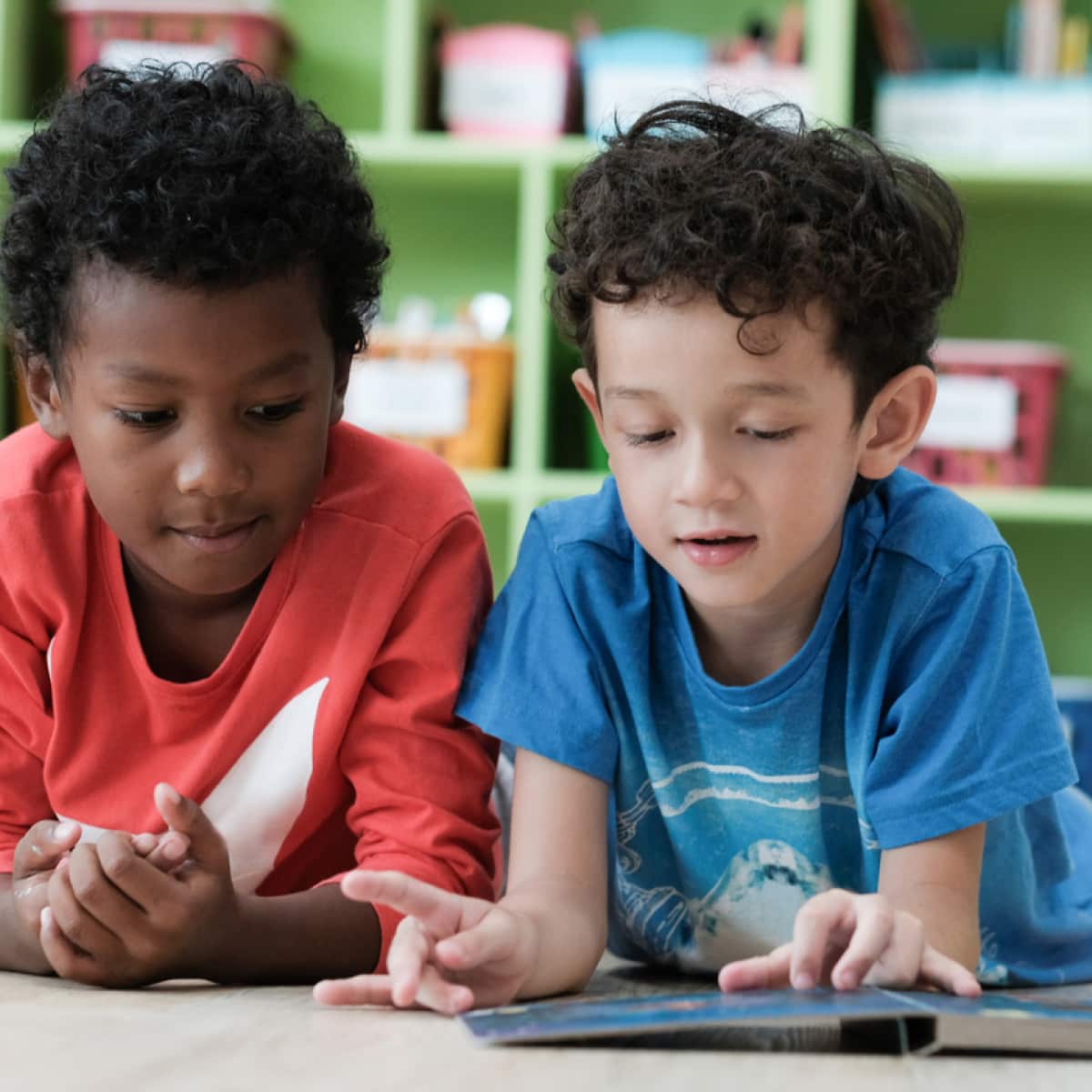 Two young boys reading a book together. 