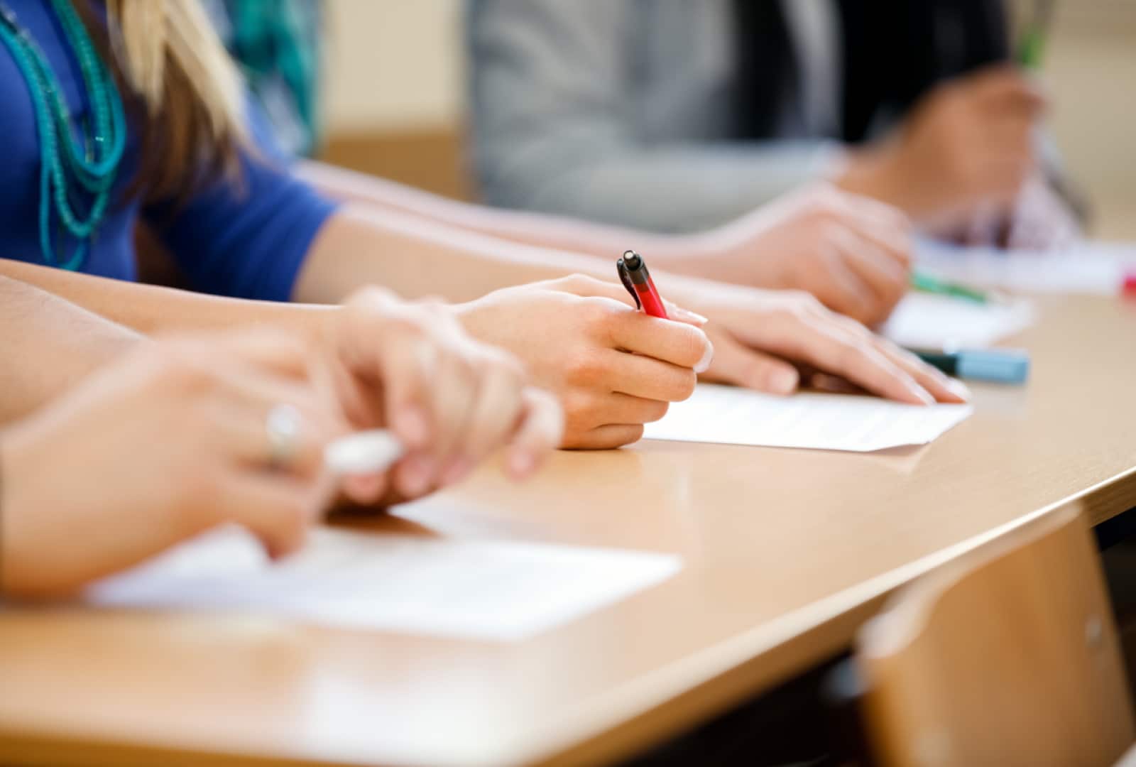 a close up of hands holding a pencil with paper in front of them on desk