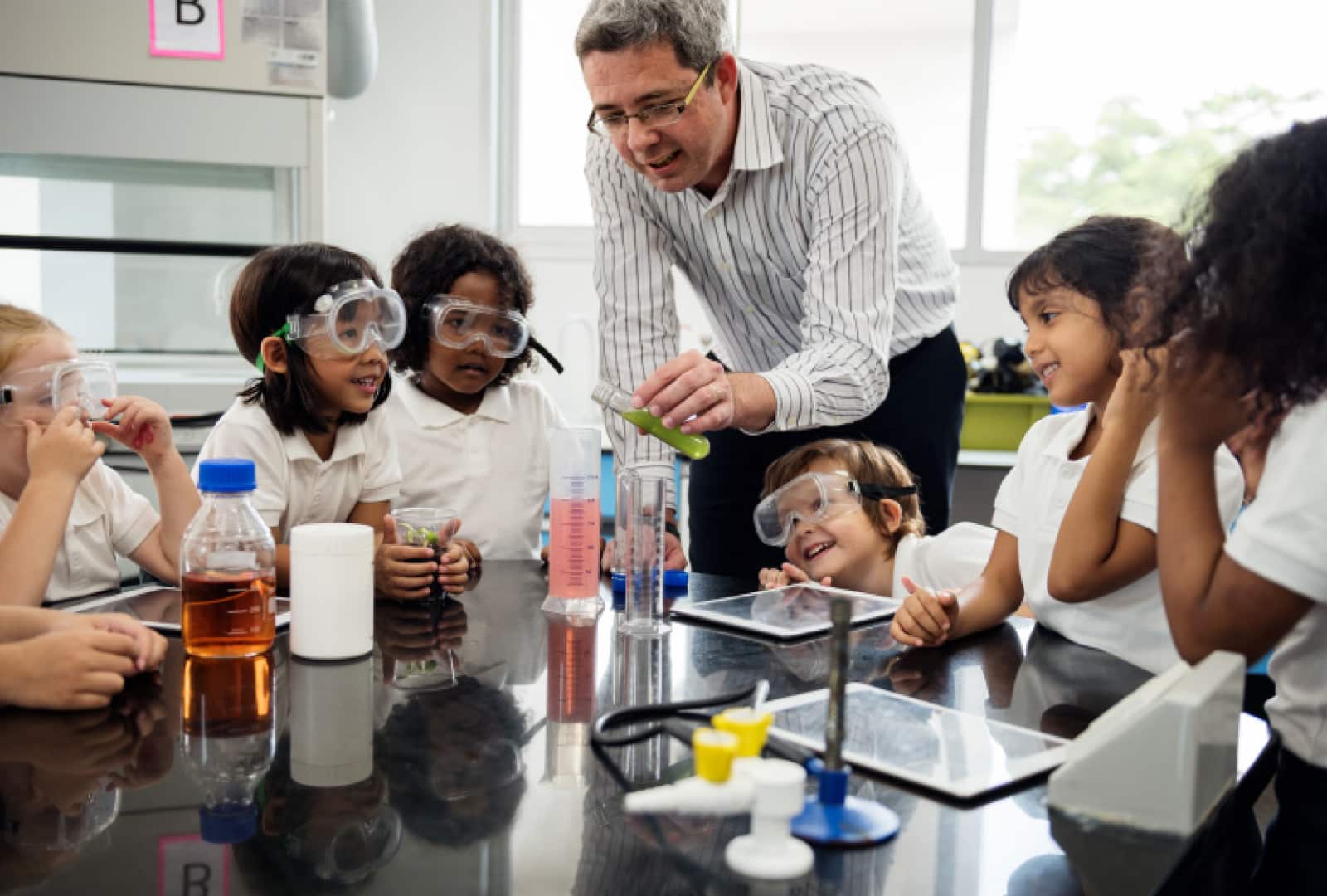 Seven students and one teacher sitting in science classroom working on science experiment. 