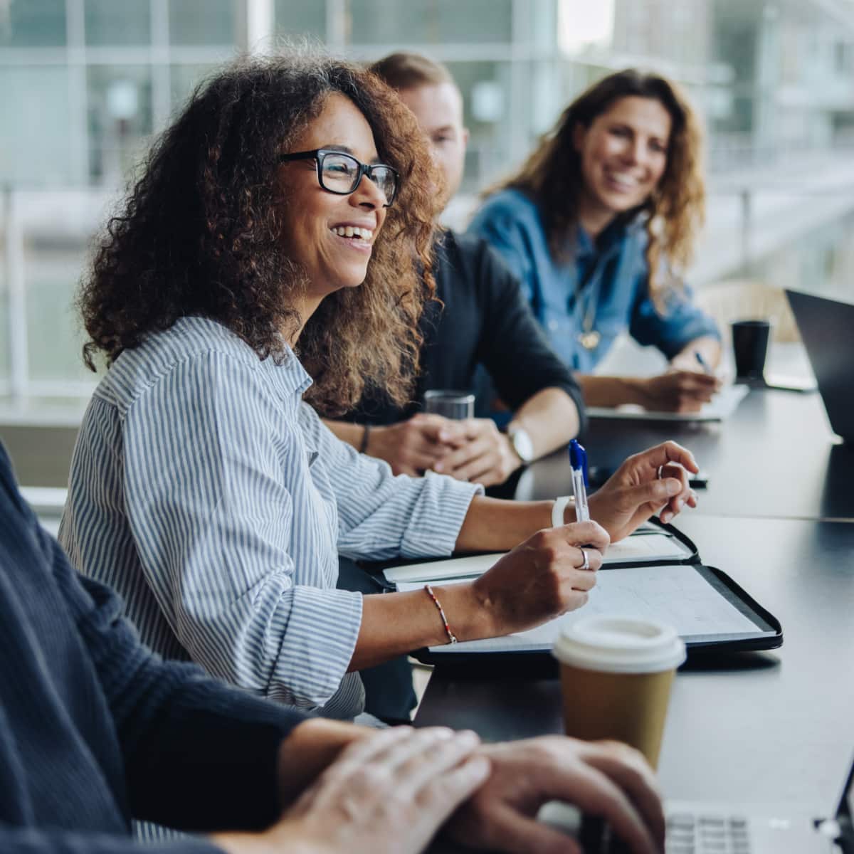 Six people sitting around desk working smiling with each other. 