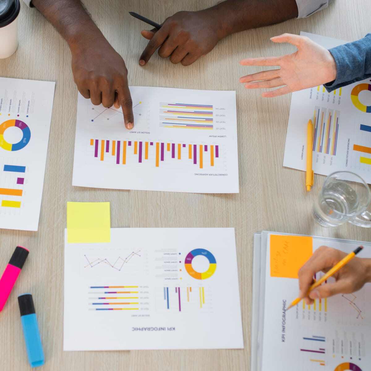 Coworkers working together at desk looking at data charts. 