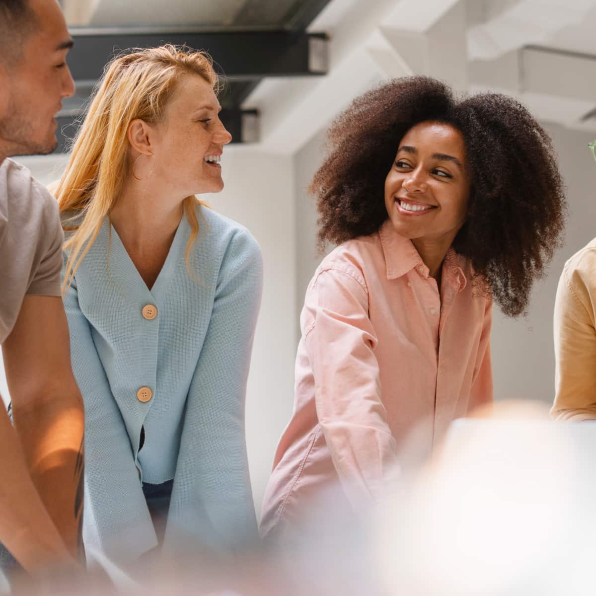 Four co workers standing side by side smiling talking with one another. 