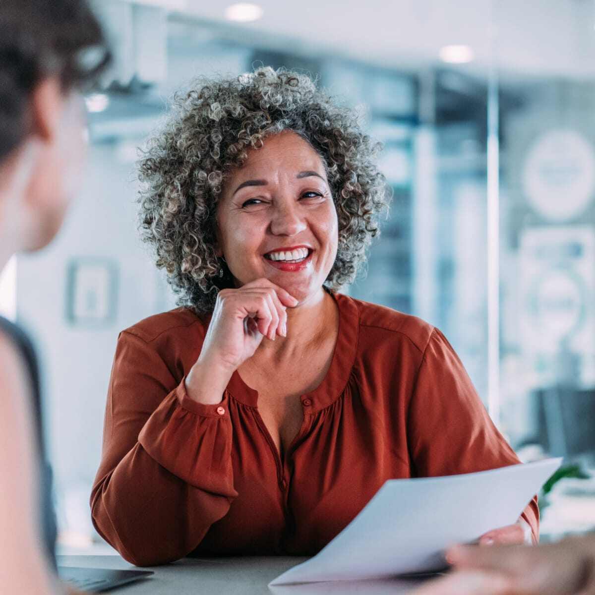 Three co workers sitting at desk working together smiling and communicating. 