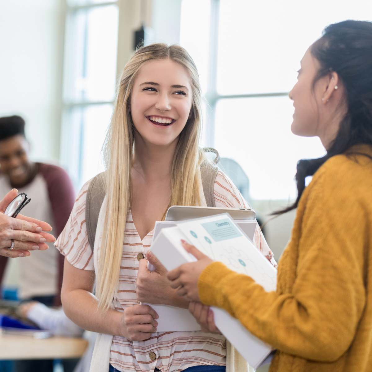 Teacher and two students standing in classroom talking. 