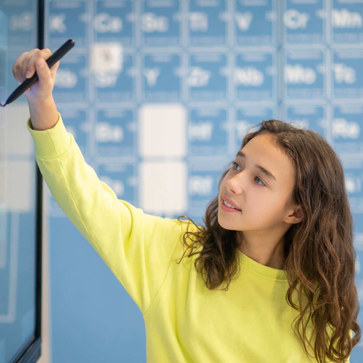 Girl writing on the smartboard in classroom. 