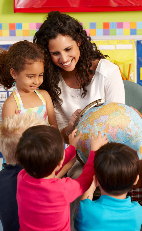 Four students looking at a globe with teacher. 