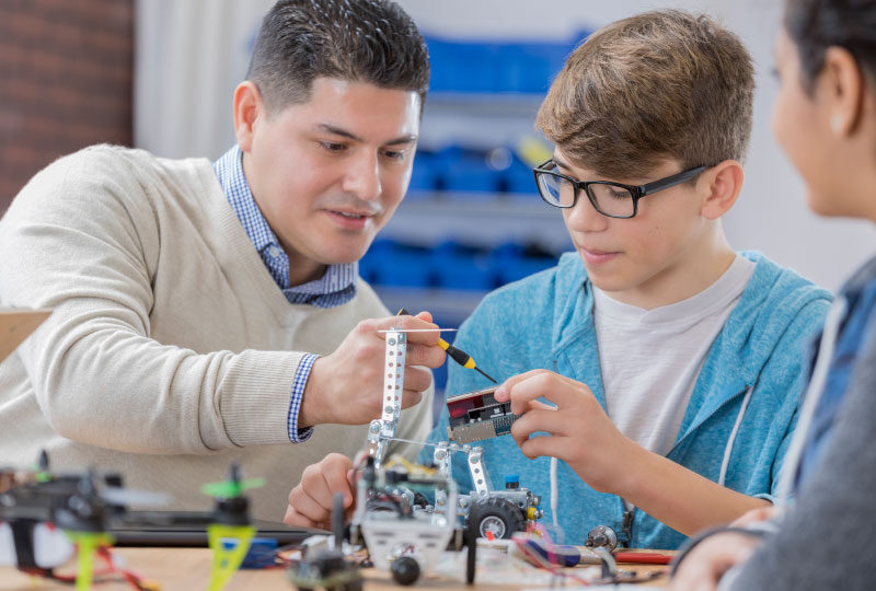 Teacher and student sitting next to each other working on robotics activity. 