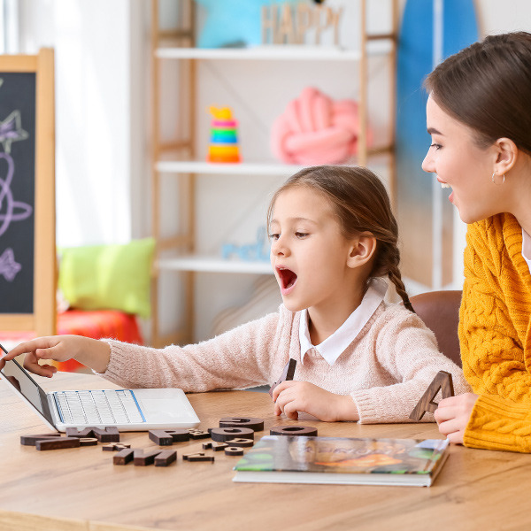 student and teacher sitting at desk looking at laptop together