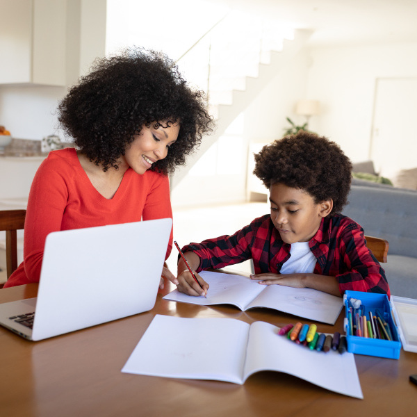 woman and child sitting around table working together writing in notebook