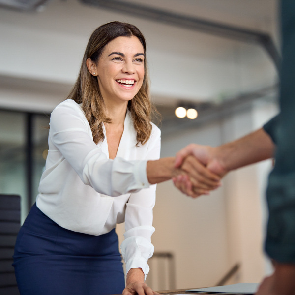 two people in office standing facing each other shaking hands