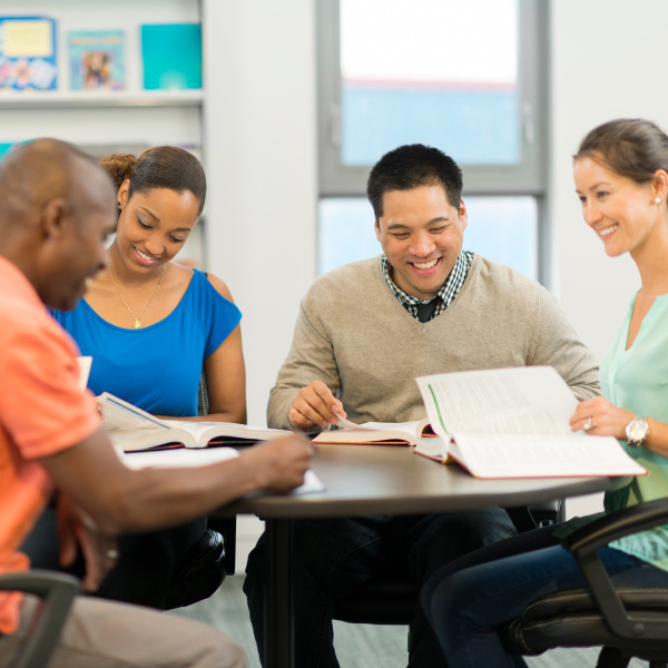 educators sitting around table working together reading books