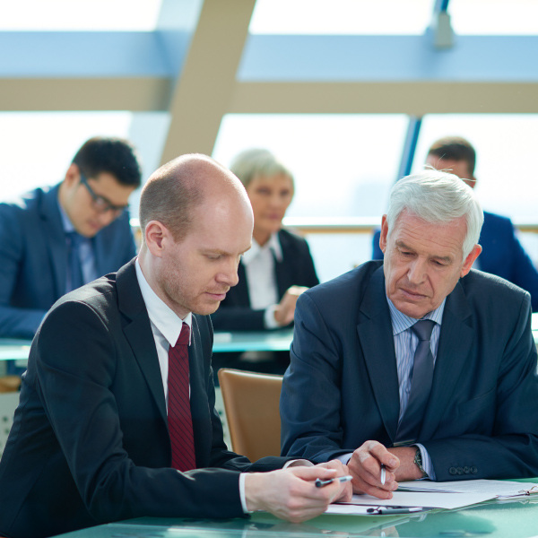 two coworkers sitting next to each other reading over documents