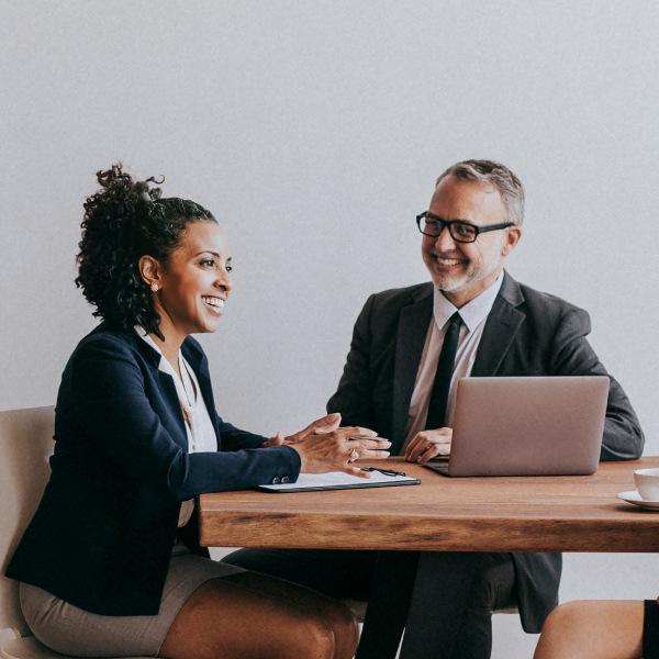 three coworkers sitting at desk in conference room having a meeting