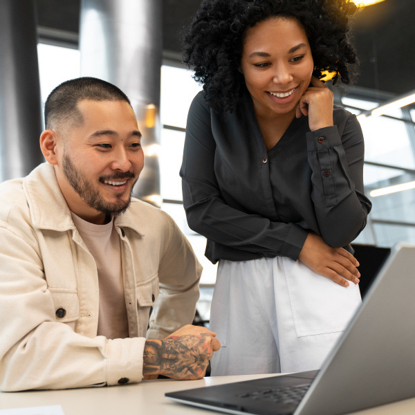 two coworkers in office working together looking at laptop