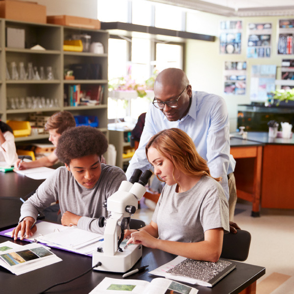 Science teacher helping two students