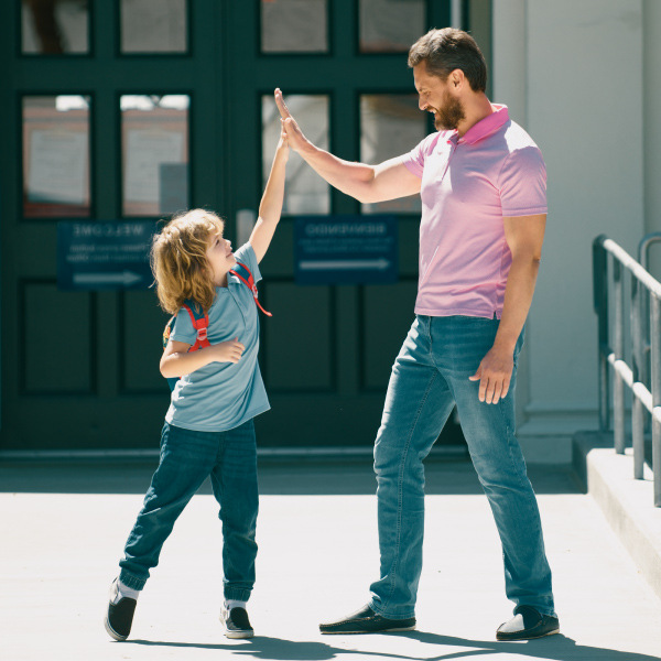 man and child standing outside facing each other doing a high five