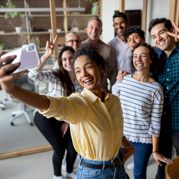 eight coworkers standing next to each other smiling taking a group selfie