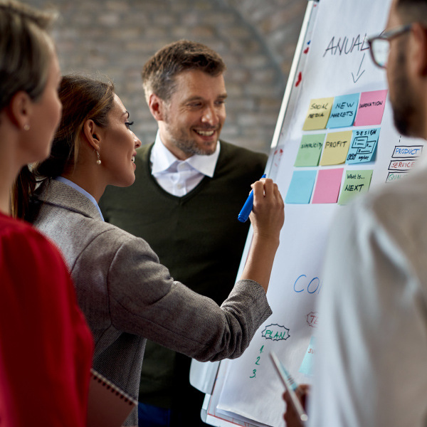 four coworkers standing next to each other working together writing on whiteboard