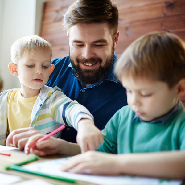 man and two boys sitting together coloring