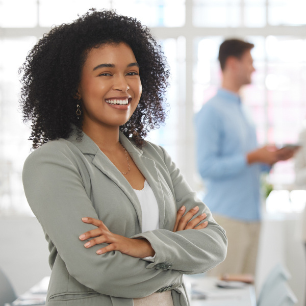 woman in conference room standing facing forward arms crossed smiling