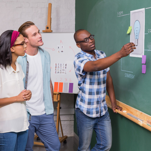 coworkers standing working together looking at a diagram on a board