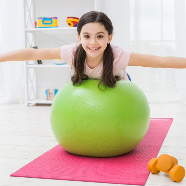 young girl balancing on exercise ball