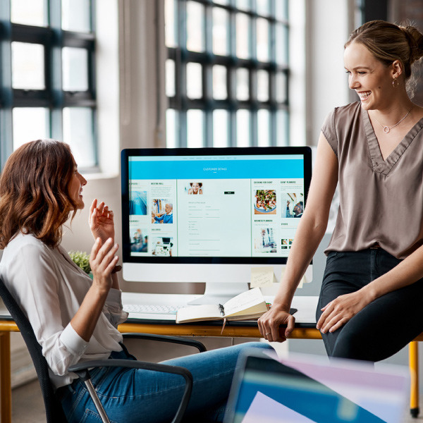 Two women talking near computer