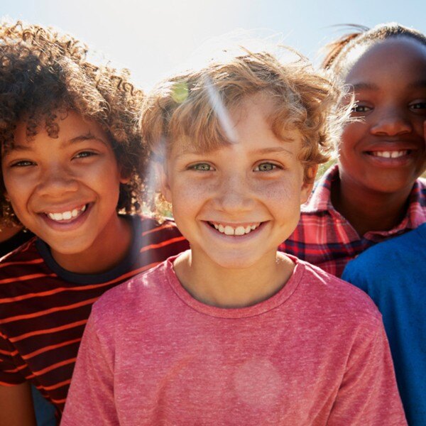 children standing side by side facing forward smiling