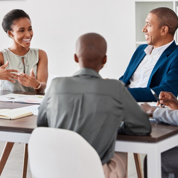 four coworkers sitting around table in conference room working together communicating