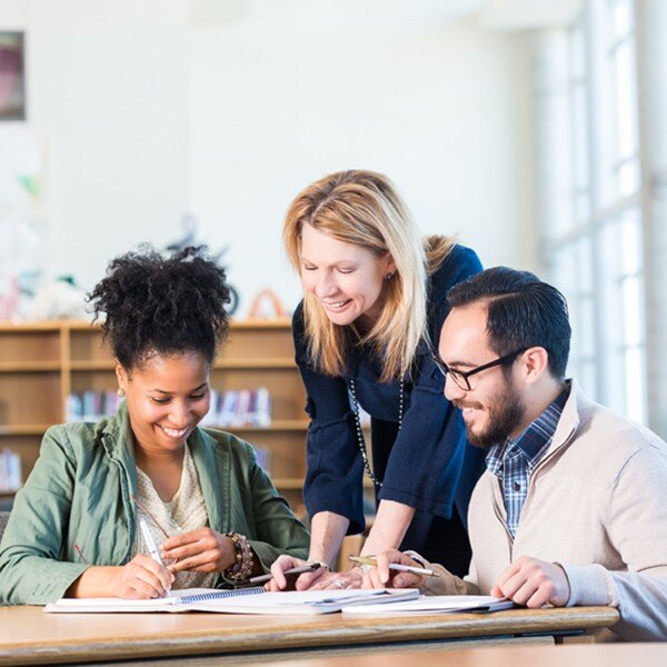 three individuals working together around desk in notebook