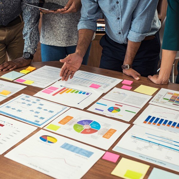 four coworkers standing looking at pieces of paper with data charts