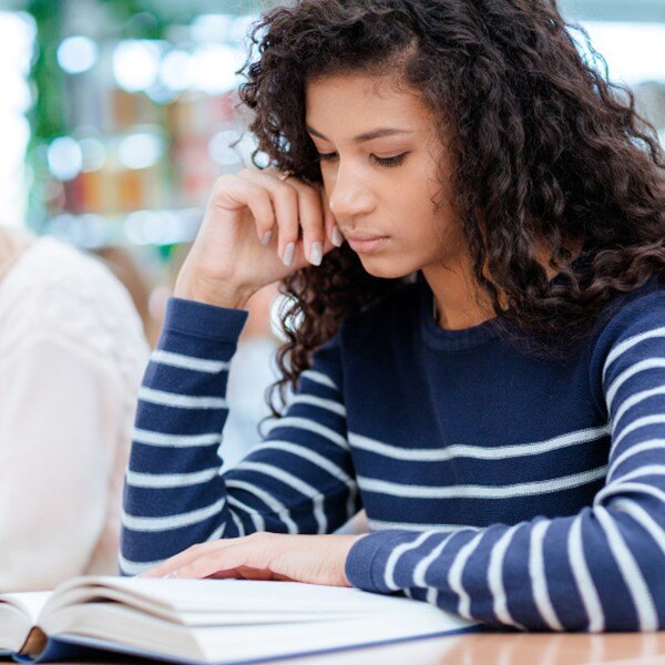 student sitting at desk in classroom reading book