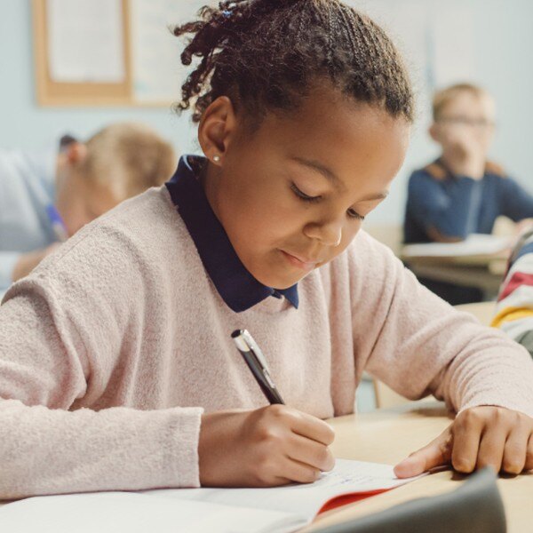 students sitting at desks in classroom writing in notebooks