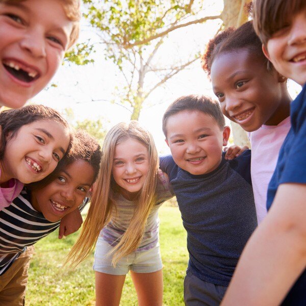 children standing in circle wrapping arms around each other smiling 