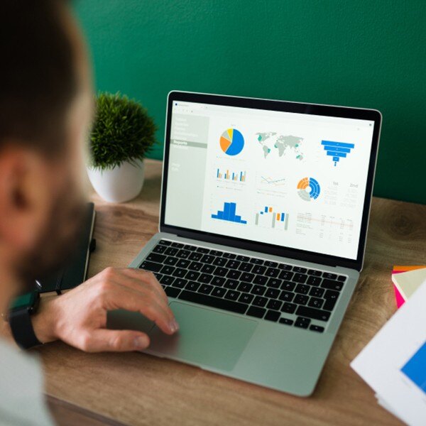 man sitting at desk working on laptop looking at charts data