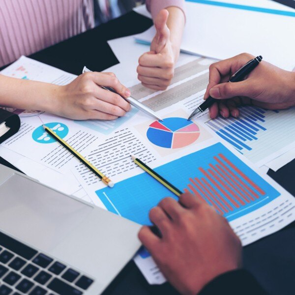 two coworkers sitting at desk in office looking at documents data charts