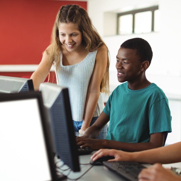 students in computer lab classroom in school working together looking at computer screen