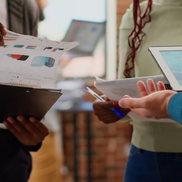 co workers holding clipboards and tablets with data and charts