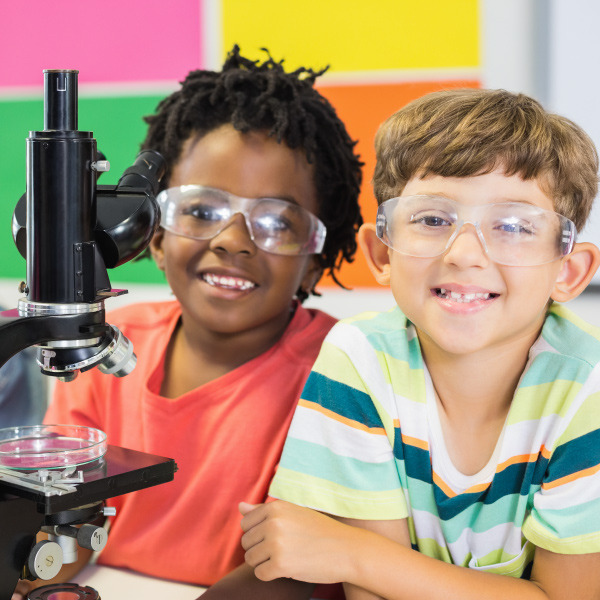 students wearing safety glasses in science class working with a microscope