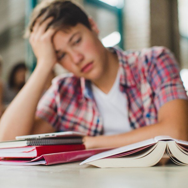 student sitting at desk in school looking at books