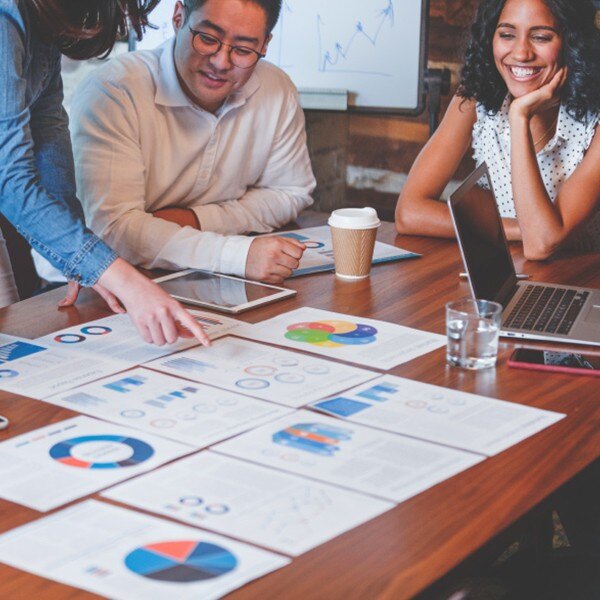 three coworkers in conference room working together communicating charts data