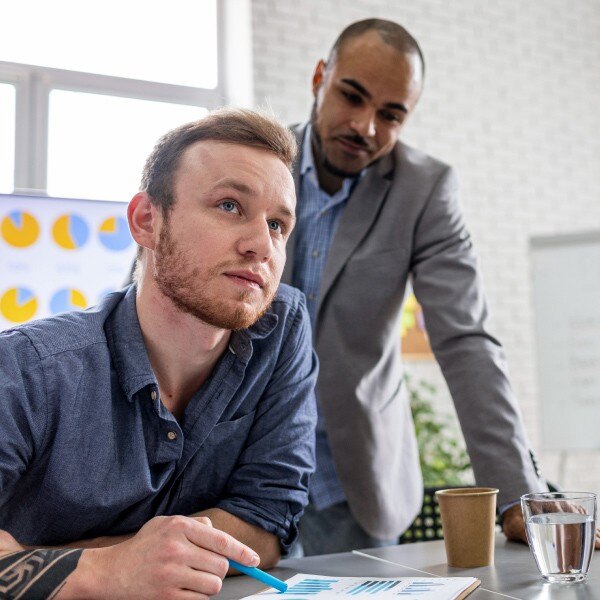 two coworkers in office working together data charts writing notebook