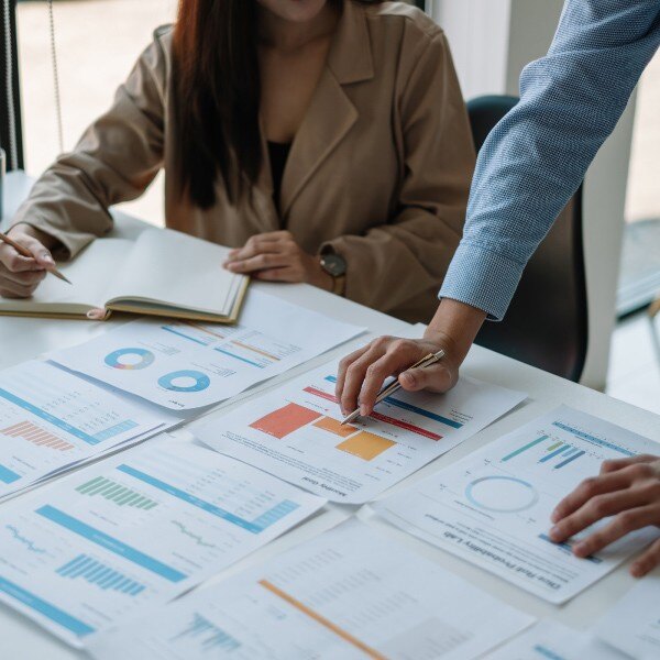 two coworkers at desk in office looking at documents data charts