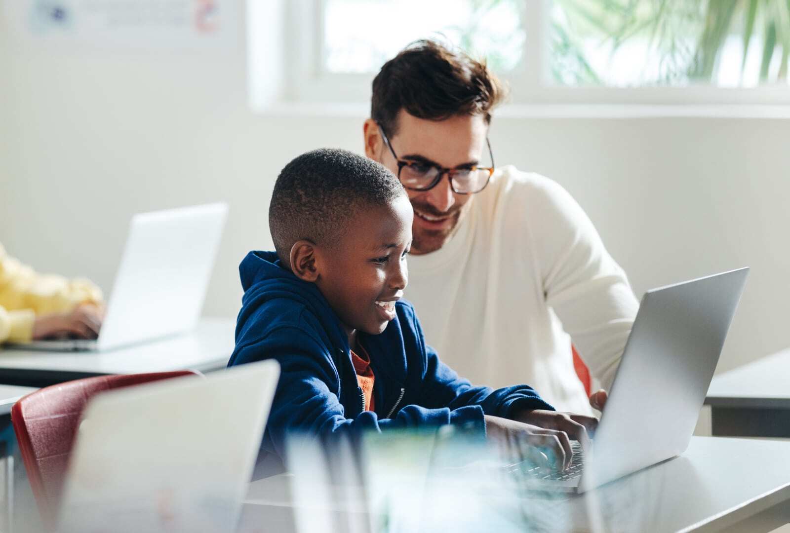 Teacher helping a student with work on his computer. 